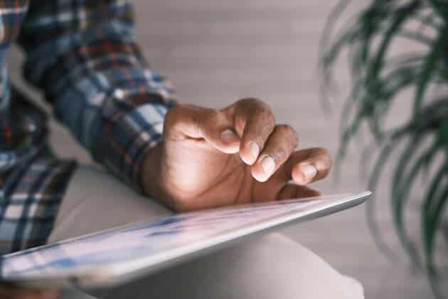 uomo con un tablet che prenota un appuntamento al consolato italiano, primo piano della mano