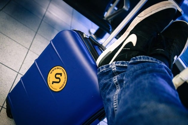 "person with feet on the suitcase waiting to depart